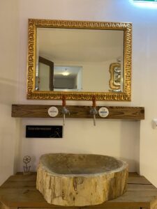 Eine Steinschale als Waschbecken mit einem goldenen Spiegel darüber