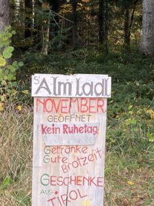 Ein Holzschild mit der Aufschrift Almladl November geöffnet und einer Speisekarte
